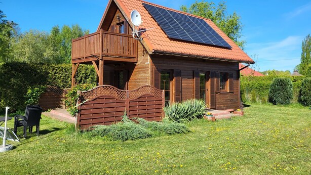 Una casa de fusta amb teulada inclinada, panells solars i antena satèl·lit.
