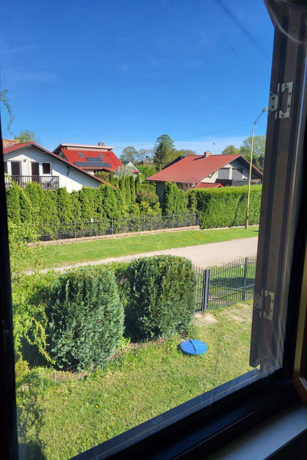 Un barrio residencial con casas, un césped cuidado y una valla metálica.