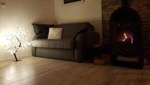 Un saló d'estar acollidor amb un sofà, una làmpada d'arbre decorativa, una llar de foc i un quadre a la paret.