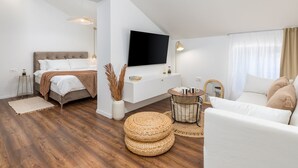 Una habitación moderna y bien iluminada con una cama, un sofá, un televisor y un comedor.