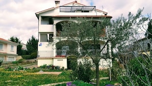 A two-story building with a balcony on the upper floor, surrounded by a garden with various plants and flowers. - Anwesen "Krasno" mit Terrasse by Interhome (Rovinj)