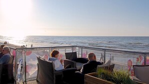 A terrace with wicker chairs overlooking the sea, a metal railing, and a clear sky. - Haus am Meer by Interhome (Krokowa)
