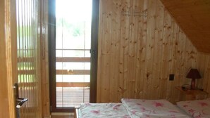 Un interior de madera con una cama, una mesita de noche y una lámpara.