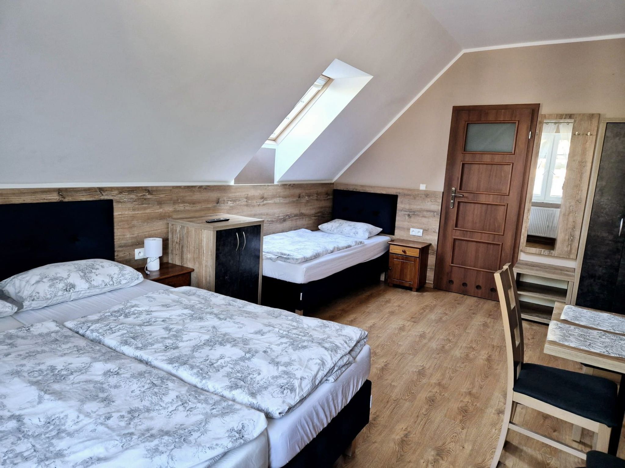 Une chambre avec deux lits, une armoire en bois, un bureau et une chaise.
