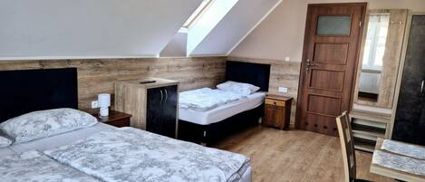 Une chambre avec deux lits, une armoire en bois, un bureau et une chaise.