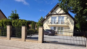 A two-story house with a balcony, a gated driveway, and a gravel path leading to the entrance. - mit Wasserblick by Interhome (Wisełka)