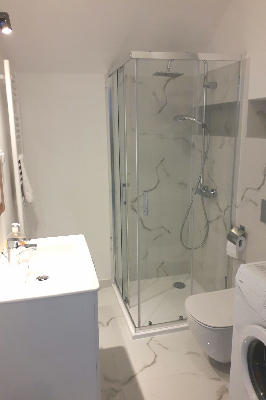 A modern bathroom with a glass-enclosed shower, a white sink, and a toilet.