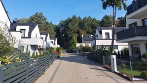 Eine Wohnstraße mit modernen Häusern, einem gepflasterten Fußweg und blauem Himmel.