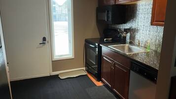 A kitchen with wooden cabinets, a microwave, a dishwasher, and a window with a view of the outside.