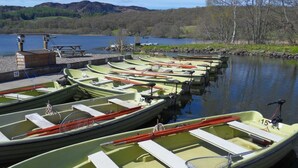 Une rangée de barques à rames, chacune portant un numéro, était amarrée à un quai, près duquel se trouvait une table de pique-nique.