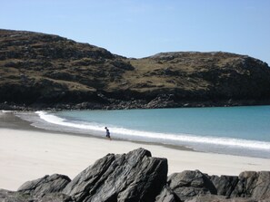 A beach with rocky outcrops and a person walking along the shore. - Rustikales Ferienhaus Shiantview by Interhome (Orinsay)