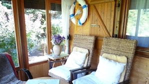 A cozy room with wicker chairs, a table with menus, and a lifebuoy on the wall. - Glücksurlaub mit Hund am See by Interhome (Rózansko)