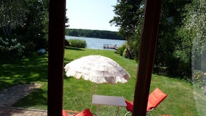 A patio with a thatched umbrella, red chairs, and a view of a lake. - Glücksurlaub mit Hund am See by Interhome (Rózansko)