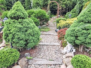 A garden pathway with neatly trimmed bushes and a stone walkway.