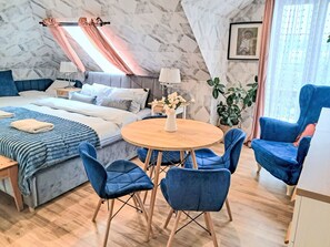 A modern bedroom with a bed, bedside table, lamp, and a round table with chairs.