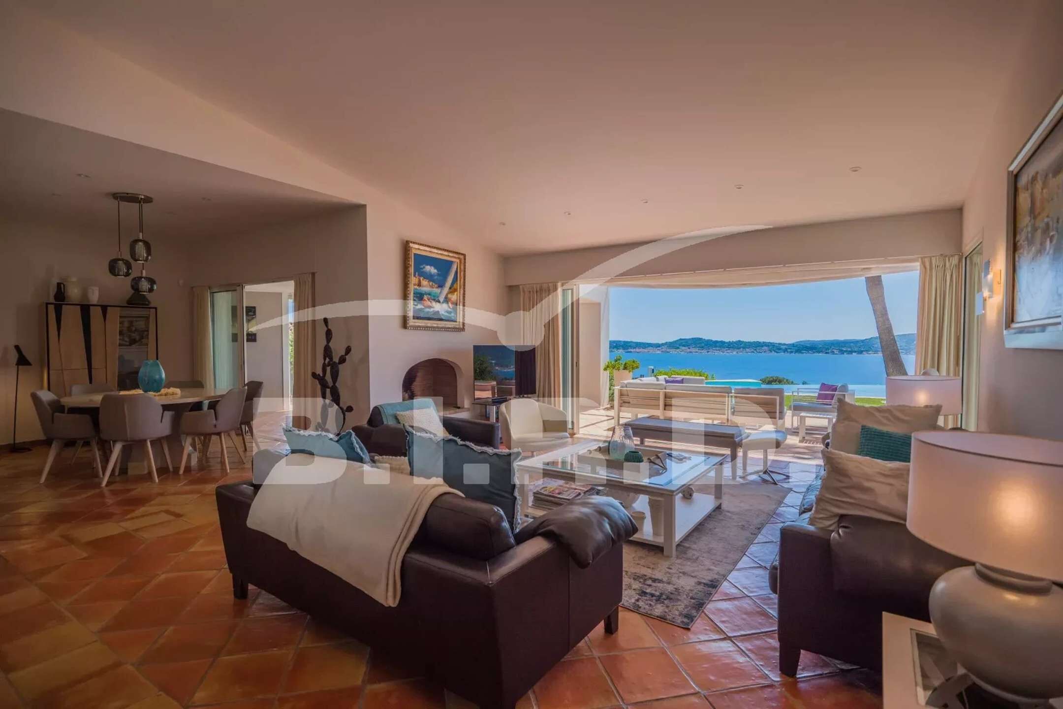 A spacious living room with a large window overlooking a scenic view, furnished with leather sofas, a coffee table, and a dining area.