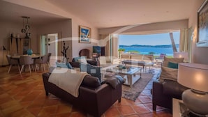 Amplia sala de estar con un gran ventanal que ofrece una vista panorámica, amueblada con sofás de cuero, una mesa de centro y un comedor.