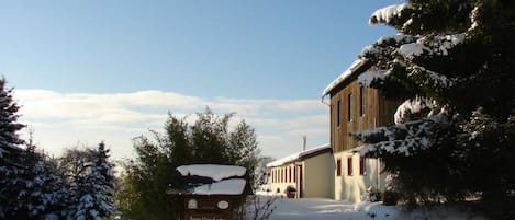 En snötäckt stuga med en skylt som visar ”Snow View Lodge” och ”Zimmer Rooms”.