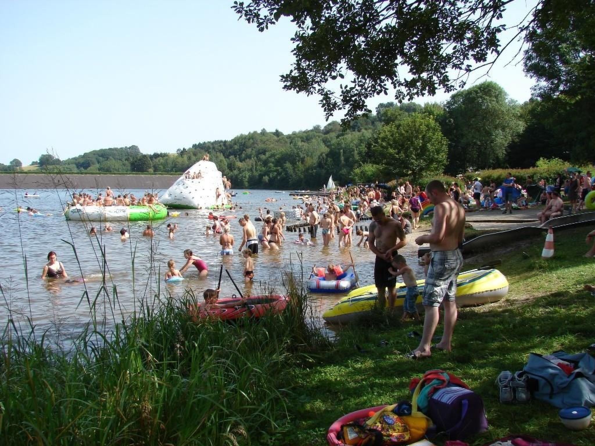 Un lac très fréquenté, où l’on voit des gens se baigner et des bateaux.