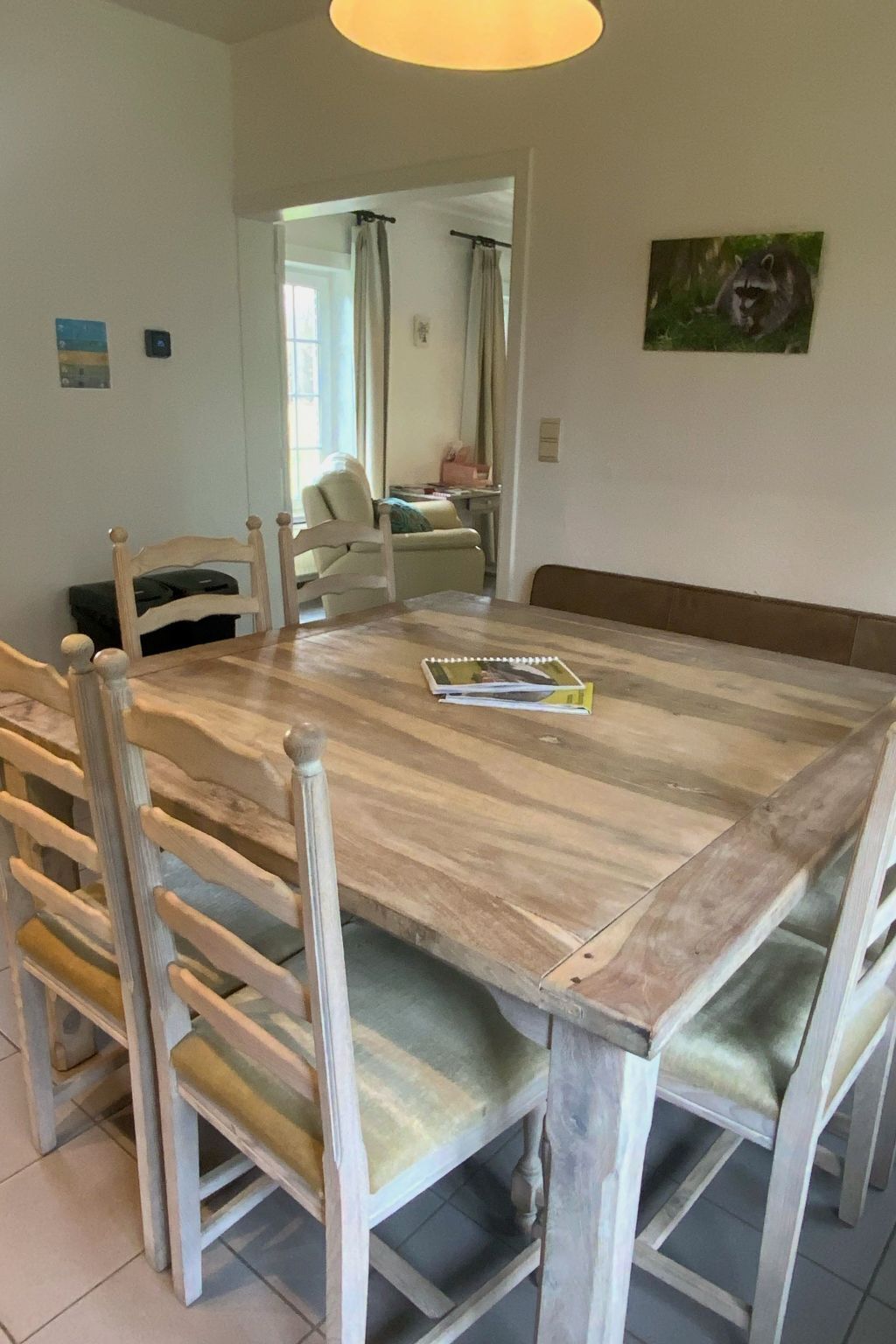 A dining area with a wooden table and chairs, a bench, and a painting on the wall.