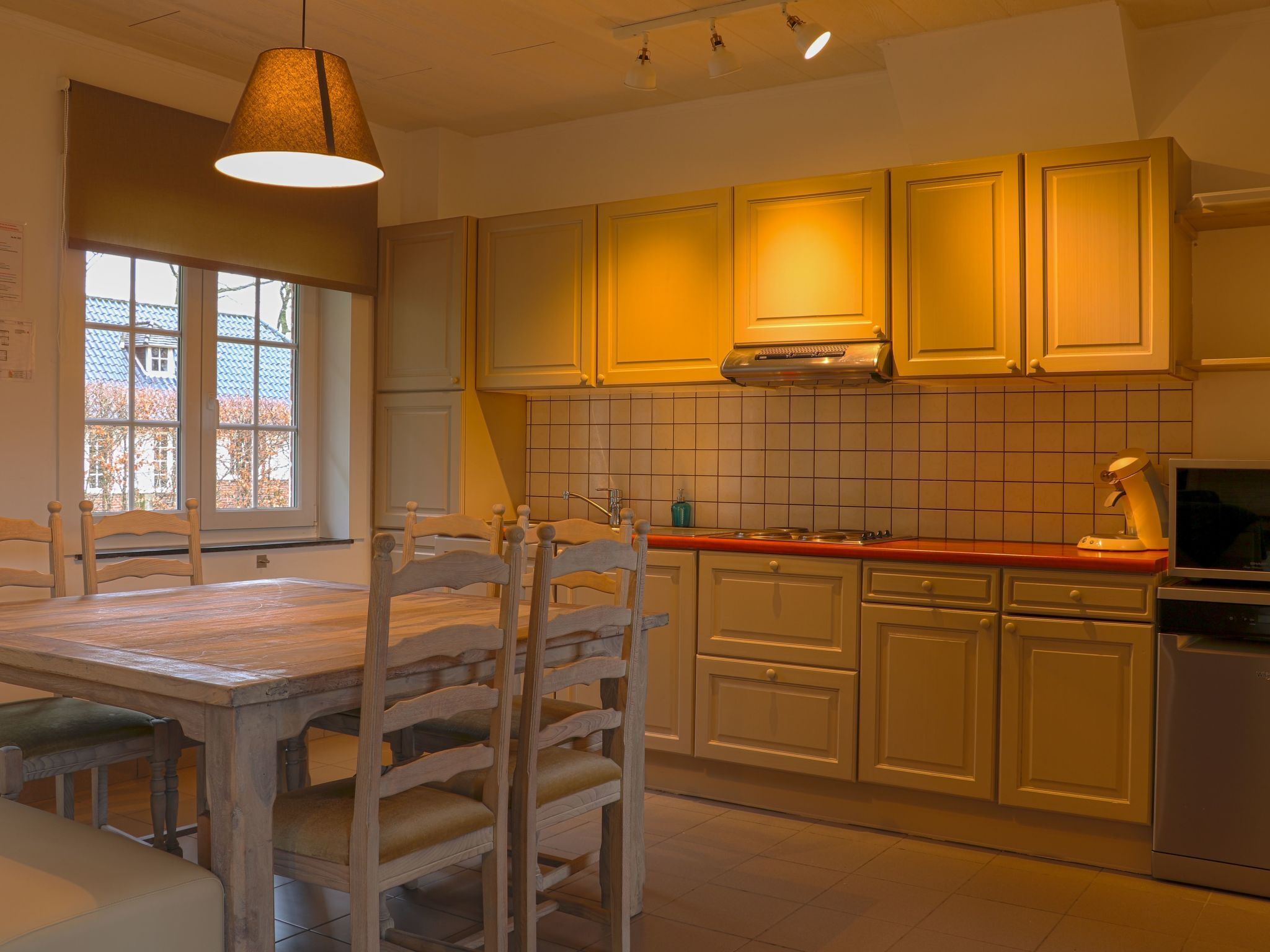 A kitchen with wooden cabinets, a stove, and a dining table with chairs.