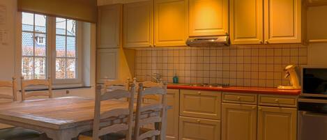A kitchen with wooden cabinets, a stove, and a dining table with chairs.