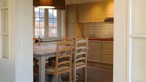 Eine Küche mit Holzausstattung, einer gefliesten Spritzschutzwand und einem Essbereich mit Holztisch und Stühlen.