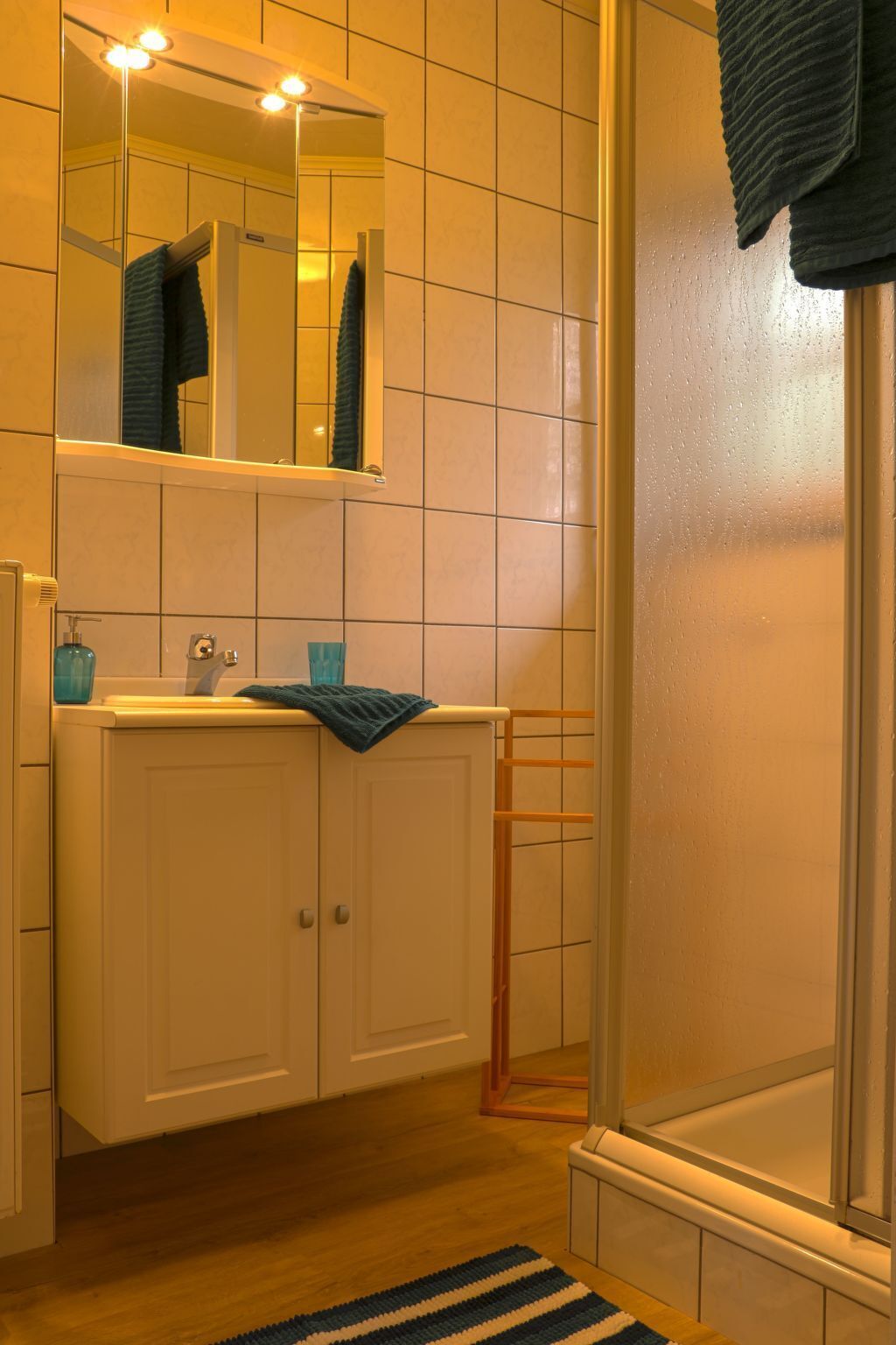 A bathroom with a sink, mirror, and shower.