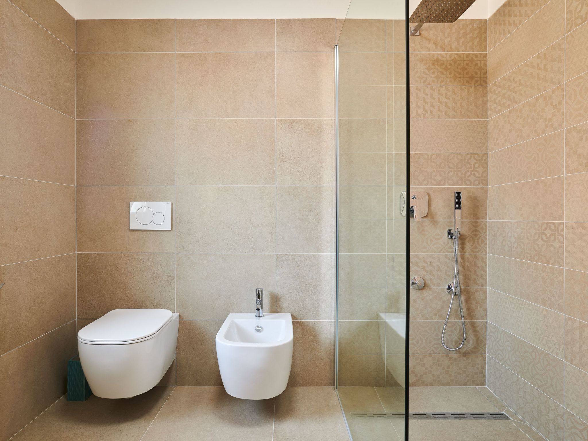 A modern bathroom with a toilet, bidet, and glass-enclosed shower area.