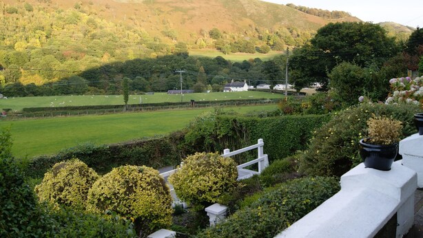 A rural landscape with rolling hills, a green field, and a white fence. - Velvet Cottage by Interhome (Pentrefelin)