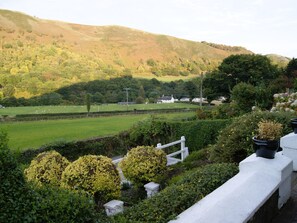 A rural landscape with rolling hills, a green field, and a white fence. - Velvet Cottage by Interhome (Pentrefelin)