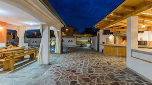 An outdoor patio area with stone flooring, wooden furniture, and a stone fireplace. - Villa Deni by Interhome (Buje)