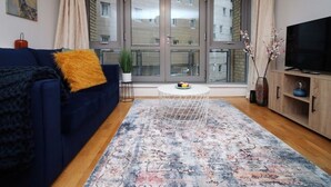 Ein modernes Wohnzimmer mit einem blauen Sofa, einem Couchtisch und einem Fernseher auf einer Holzkommode.