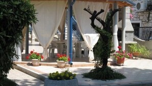A covered outdoor seating area with potted plants and a tree. - Wohnung mit Blick auf das Wasser by Interhome (Umag)