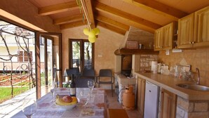 Una cucina rustica con travi in legno, un piano di lavoro in pietra e un'area pranzo con tavolo apparecchiato per due.