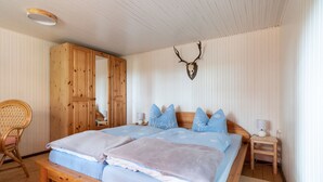 A bedroom with a large bed, wooden wardrobe, and a deer skull on the wall. - Blockhütte Rudolf by Interhome (Zernitz)