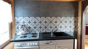 A compact kitchen with a stove, sink, and white cabinets. - Blockhütte Rudolf by Interhome (Zernitz)