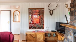 A cozy living room with a wooden cabinet, a television, and a stone fireplace. - Blockhütte Rudolf by Interhome (Zernitz)