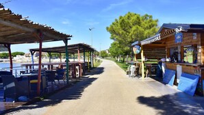 Une promenade en bord de mer avec des espaces de repos abrités et un bar.