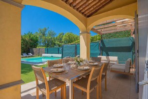 An outdoor patio with a pool, dining table set for four, and lounge chairs. - Semi-Detached House with Pool – 3 Bedrooms (GRIMAUD)