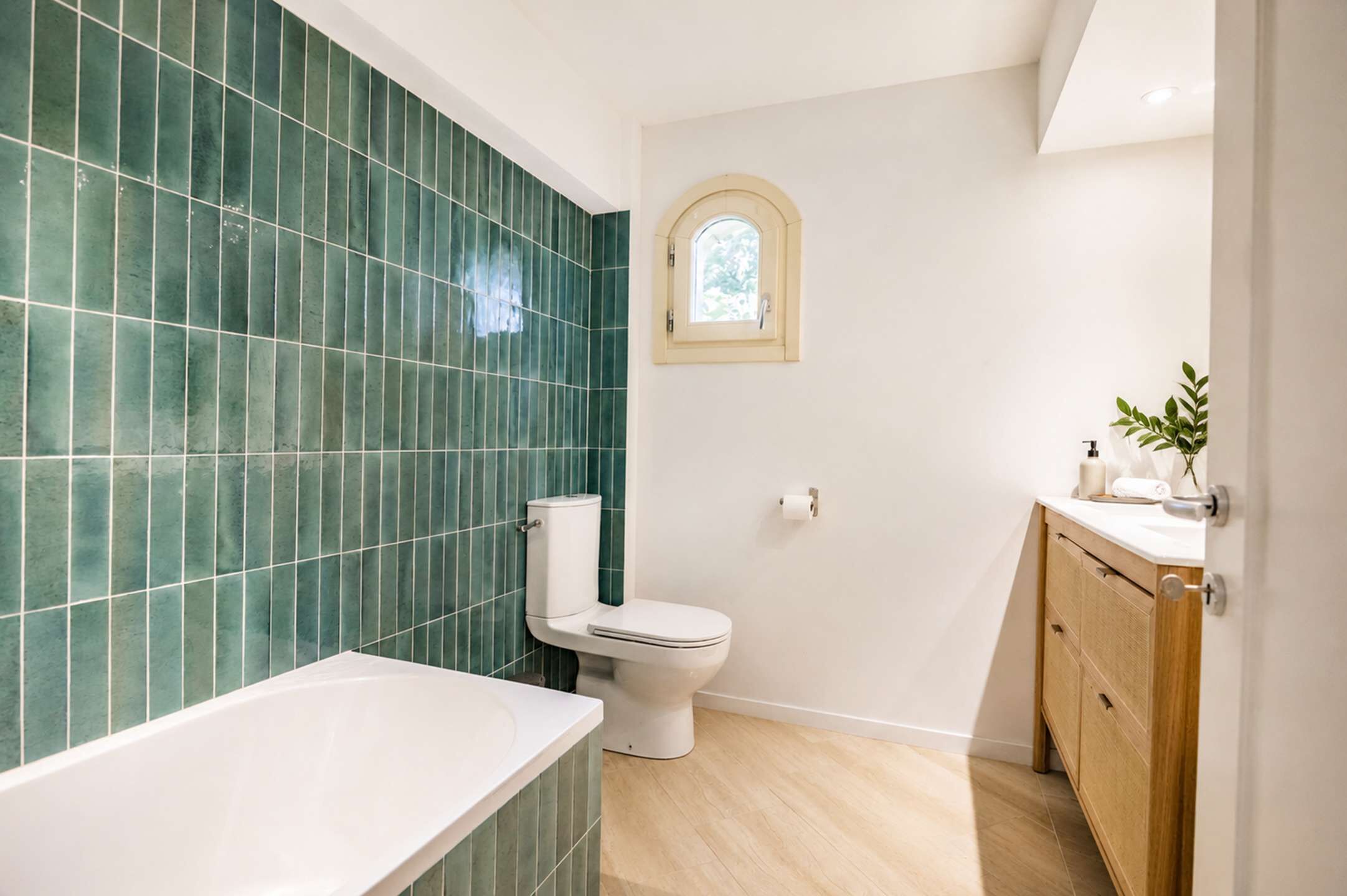 A bathroom with a white bathtub, a toilet, and a vanity with a mirror.