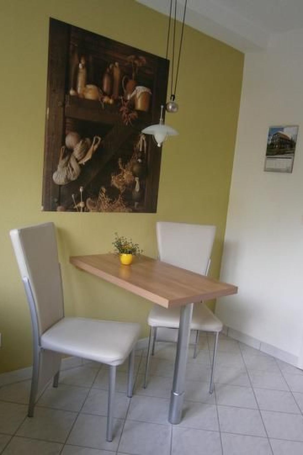 Un coin repas comprenant une table en bois et quatre chaises, un luminaire suspendu et un élément décoratif mural.