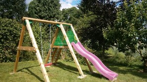 A wooden swing set with a slide in a grassy area with trees in the background. - Kottmarsdorf by Interhome (Kottmarsdorf)