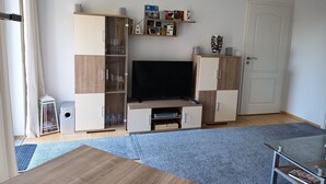 A modern living room with a flat-screen TV, wooden cabinets, a glass coffee table, and a blue carpet. - Kottmarsdorf by Interhome (Kottmarsdorf)