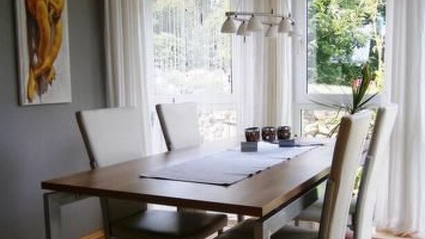 A dining area with a wooden table and chairs, a painting on the wall, and a window with curtains. - Kottmarsdorf by Interhome (Kottmarsdorf)
