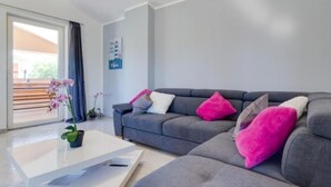 A modern living room with a grey sofa, white and pink cushions, a white coffee table, and a potted orchid. - "Haus Piljan" by Interhome (Bokordici)
