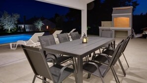 An outdoor patio with a pool, lounge chairs, a table, and a barbecue grill. - "Haus Piljan" by Interhome (Bokordici)