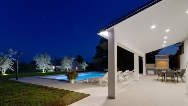 A modern outdoor patio with a pool, lounge chairs, and a barbecue area. - "Haus Piljan" by Interhome (Bokordici)
