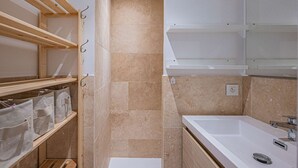 Un bany amb banyera, un lavabo i prestatges amb bosses d'emmagatzematge.