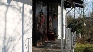 Entrada d'un edifici amb un porxo cobert, una barana metàl·lica i dos guirlands penjats a la paret.